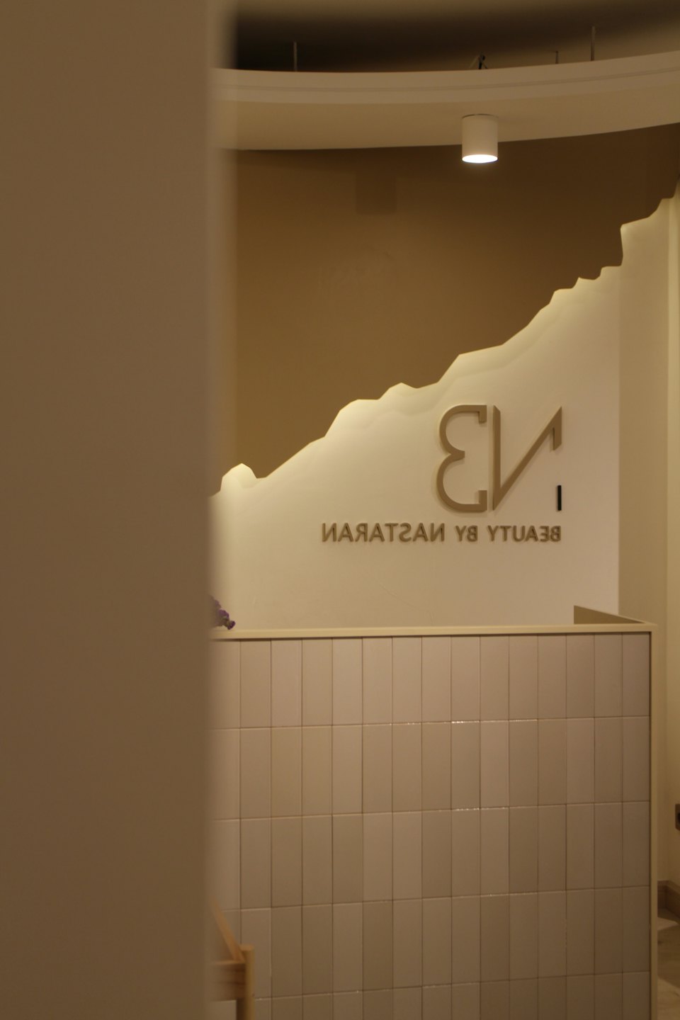 Reception area with 'BEAUTY BY NASTARAN' logo on wall.