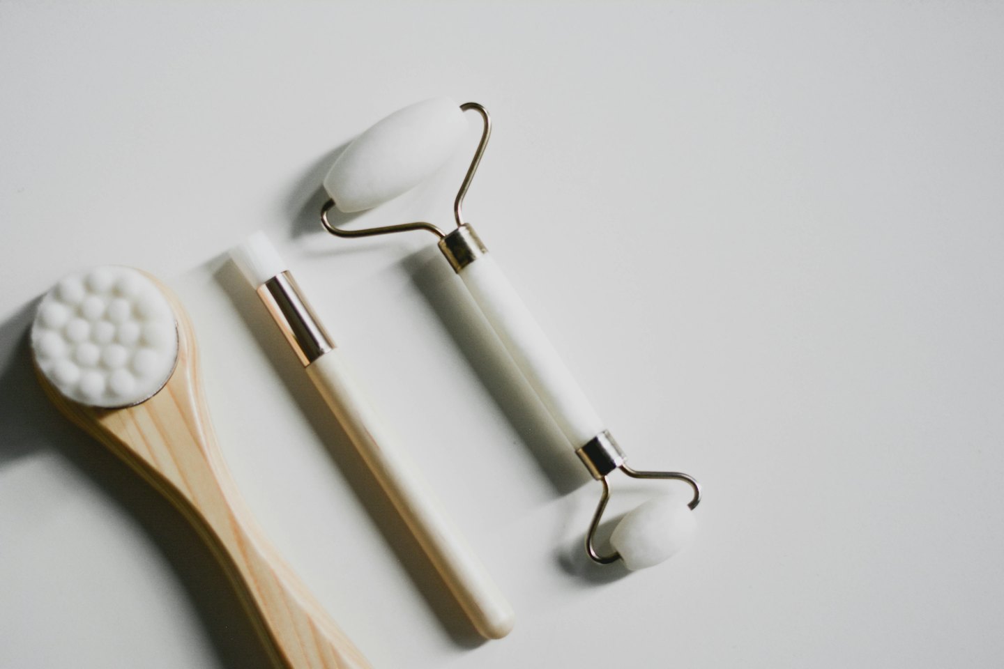 Skincare tools including a jade roller and brushes on a white background.